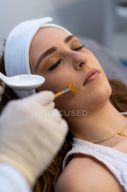 Cosmetologo di coltura anonimo che applica il peeling acido su faccia di cliente femminile durante visita in clinica di bellezza — Foto stock