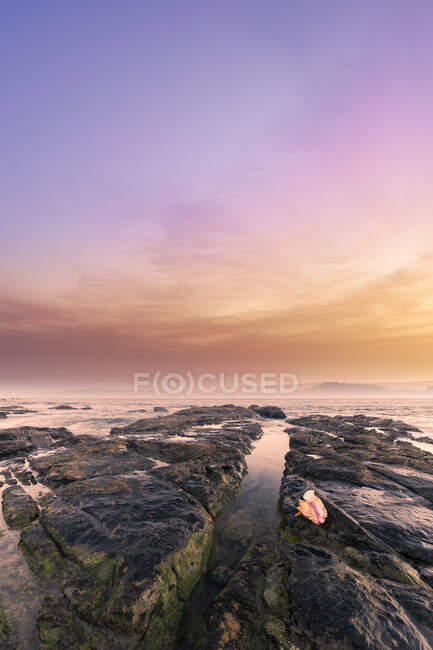 Wonderful scenery of rocks on Ribadesella coast under colorful sky at sunset in Asturias — Stock Photo