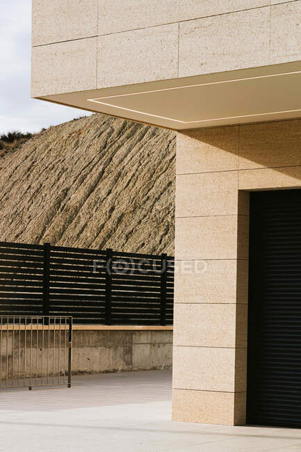 Edificio in muratura contemporanea esterno con balcone recintato contro il monte e passerella — Foto stock