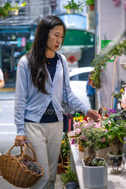 Hermosa chica asiática comprando flores en tienda de flores - foto de stock