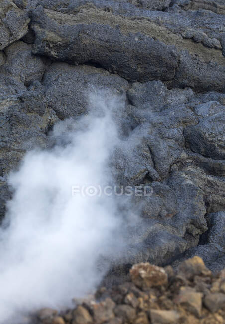 Primer plano columnas de humo y magma chispas del volcán Fagradalsfjall mientras corren como ríos de lava sobre el suelo en Islandia - foto de stock