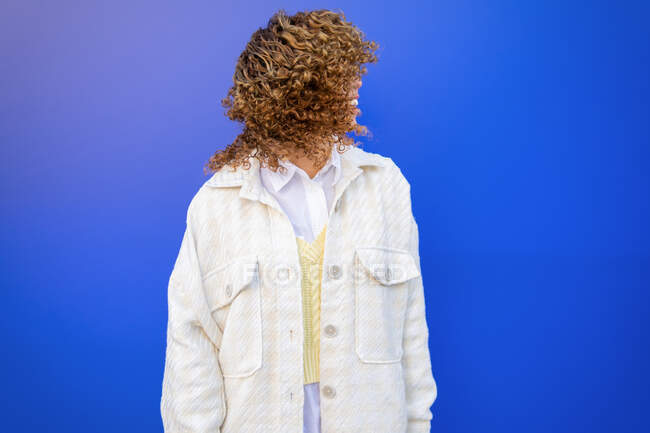 Delighted African American female with flying curly hairstyle standing on blue background in studio — Stock Photo