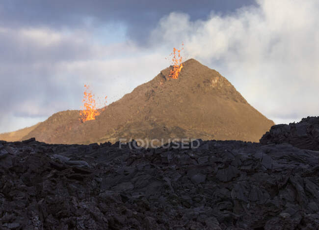 Side view of magma sparks out of the volcano hole and run like rivers of lava over the ground in Iceland — Stock Photo
