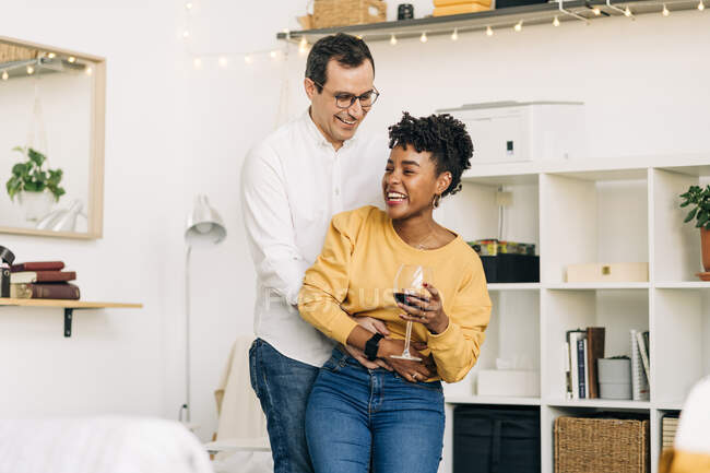 Delighted multiracial couple dancing in living room while spending time together at home — Stock Photo