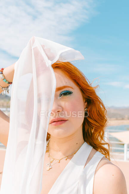 Молода жінка з рудим волоссям прикриває очі завісою, дивлячись на камеру в день весілля — стокове фото