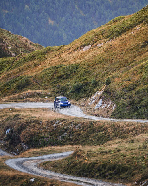 Automóvil moderno conduciendo por sendero polvoriento en verdes montañas de Pirineos con bosque en España - foto de stock