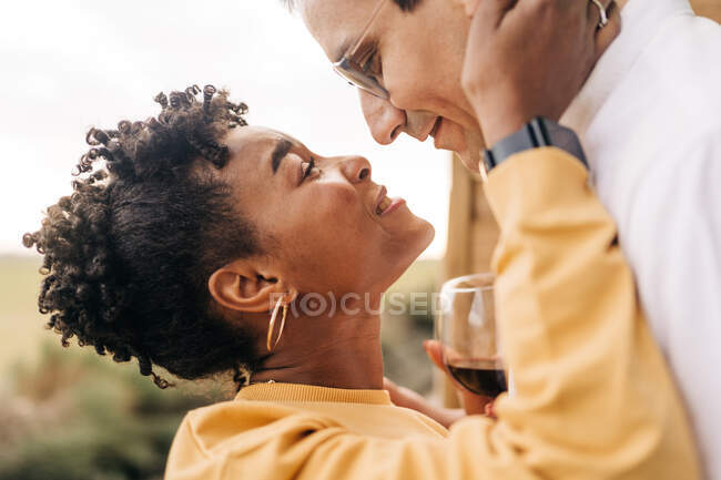 Visão lateral mulher negra feliz olhando para o homem com amor enquanto está na natureza — Fotografia de Stock