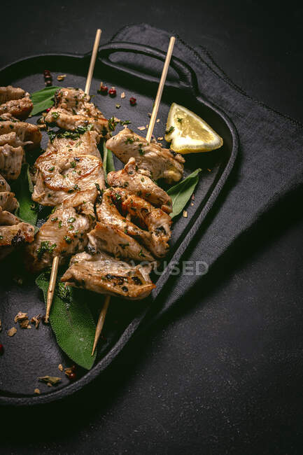 From above of appetizing freshly cooked meat on skewers served on tray on black table — Stock Photo