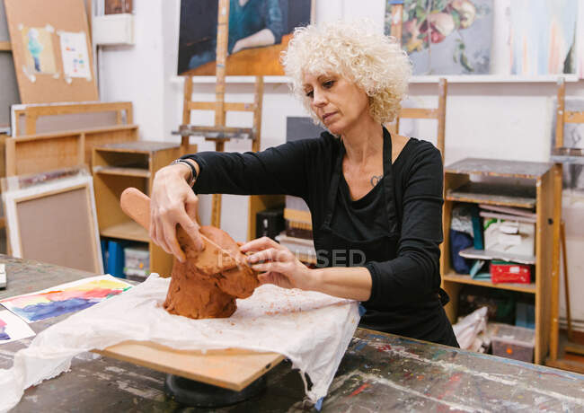 Keramikerin mit Ton und handgefertigten Töpferwaren im Kunstatelier — Stockfoto