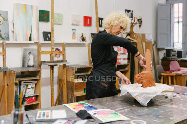 Keramikerin mit Ton und handgefertigten Töpferwaren im Kunstatelier — Stockfoto