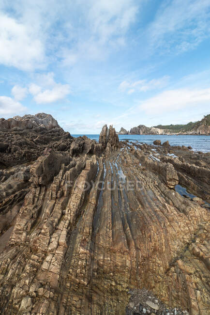 Vista panorámica de formaciones rocosas en la playa de Gueirua cerca del mar tranquilo bajo el cielo azul de Asturias - foto de stock