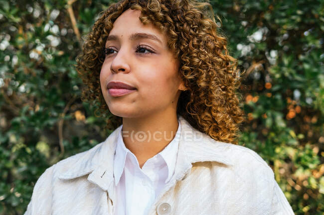 Dreamy African American female standing looking away in green summer park and enjoying nature — Stock Photo