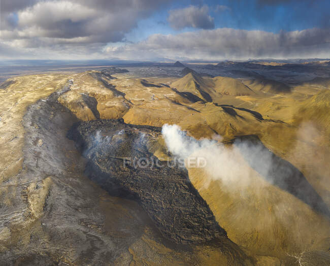 Сверху столбы дыма и магмы искрит из вулканической ямы и течет, как реки лавы над землей в Исландии — стоковое фото