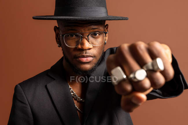 Young masculine unshaven African American male with naked abdomen in jacket looking at camera on brown background — Stock Photo