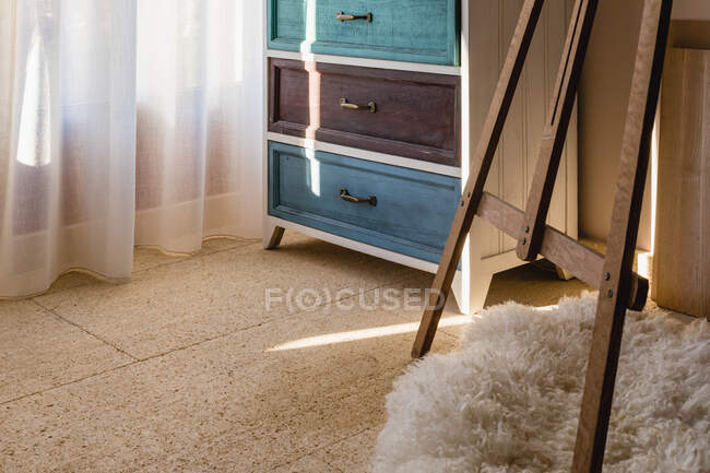 Piante in vaso e teschio decorativo su cassettiera contro tenda e soffice tappeto in casa — Foto stock