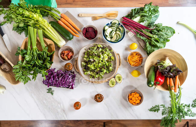 Draufsicht auf gesamtes und geschnittenes Gemüse zur Salatzubereitung auf Marmortisch — Stockfoto