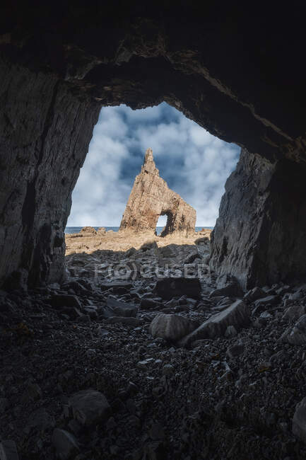 Жорсткий печерний краєвид гострої скелі з отвором на кам'яному пляжі Кампіехо під синім небом в Астурії. — стокове фото