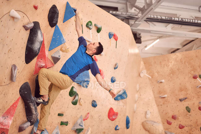Низький кут м'язового чоловіка альпініста, що звисає на скелелазінні стінки під час тренування в центрі валуна — стокове фото
