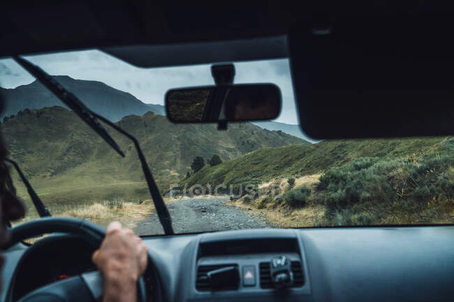 Crop anonymous male driving vehicle on route in majestic Pyrenees mountains during rain — Stock Photo