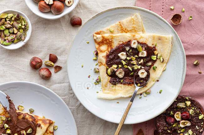 Верхній вигляд смачних млинців з шоколадом і горіхами подається на тарілці на сніданок. — стокове фото