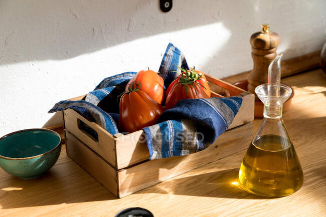 Hohe Winkel der frischen reifen roten Tomaten auf natürlichem Holztablett mit Serviette in der heimischen Küche platziert — Stockfoto
