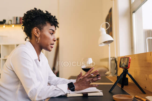 Сторона зору афроамериканської письменниці в зошиті під час перегляду онлайн-підручників через мобільний телефон вдома. — стокове фото