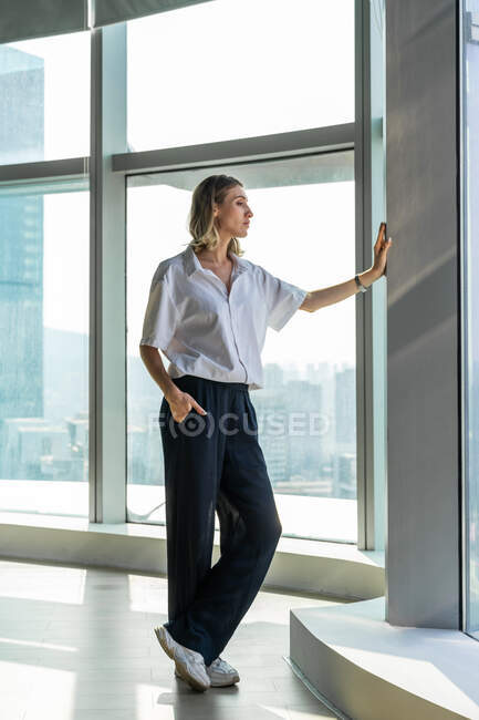 Einsames Mädchen in leerem Büro beobachtet die Stadt aus dem großen Fenster — Stockfoto