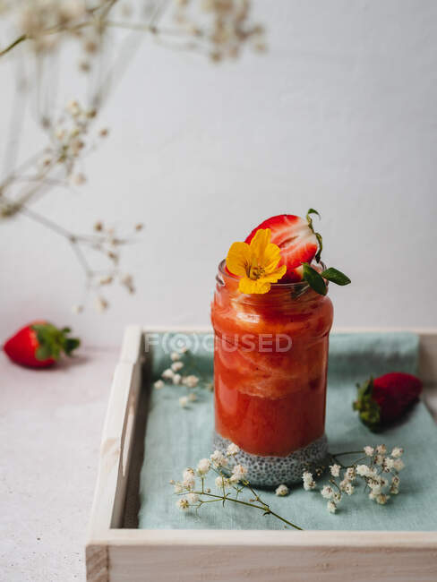 Gros plan d'un délicieux smoothie aux fraises avec une garniture de fleurs jaunes — Photo de stock