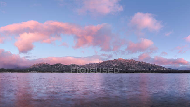 Paisagem espetacular de lago calmo e cume de montanha sob o céu crepúsculo com nuvens cor-de-rosa no Parque Nacional Sierra de Guadarrama — Fotografia de Stock