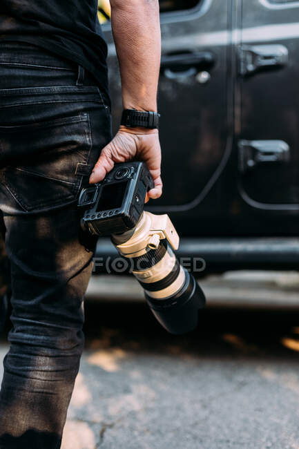 Передній вид анонімного фотографа, який тримає камеру в напрямку своєї позашляхової машини. — стокове фото