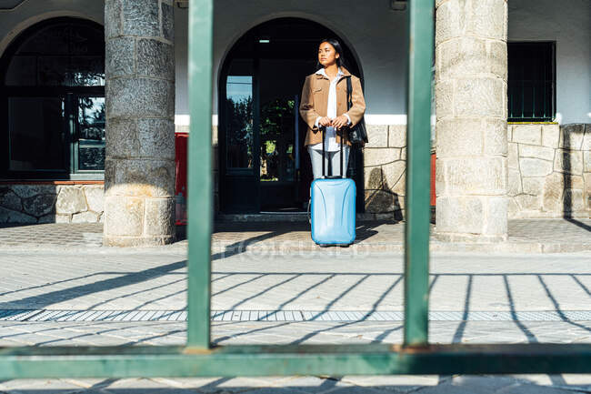 Asiática viajante feminino com mala em pé na plataforma da estação ferroviária enquanto espera o trem — Fotografia de Stock