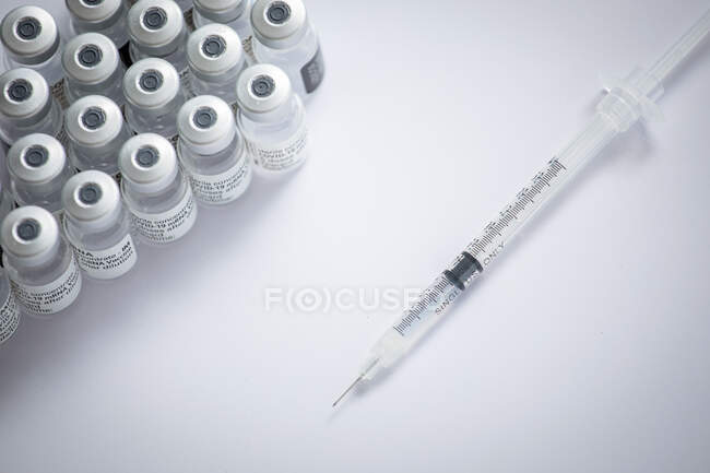 Gros plan de quelques flacons avec le vaccin contre le coronavirus et une aiguille sur fond blanc — Photo de stock