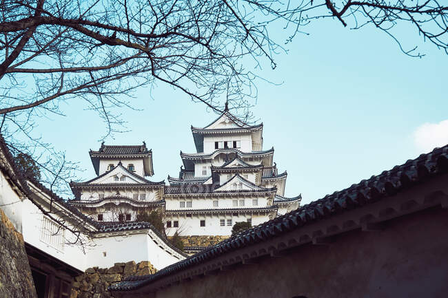 Знизу традиційного замку Хімеджі з вигнутими дахами на тлі синього неба в Японії. — стокове фото