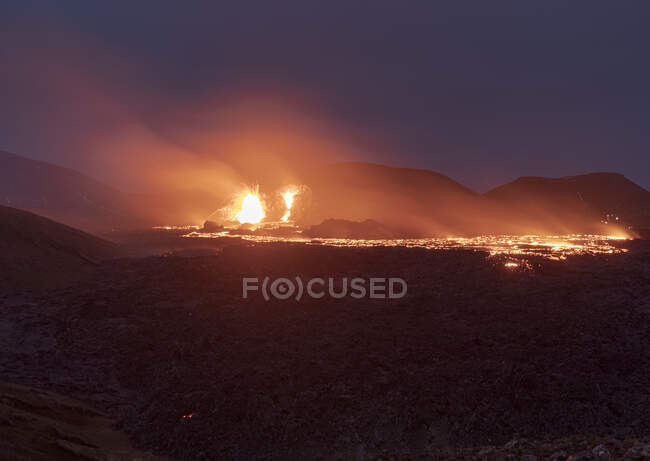 Сверху магма искрится из вулканической ямы и течёт как реки лавы по земле в Исландии. — стоковое фото