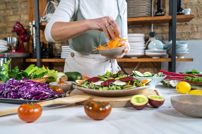 Ernte unkenntlich Weibchen mit roher Karotte bereitet vegetarisches Essen im Haus moderne Küche — Stockfoto
