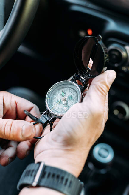 Анонімний авантюрист тримає компас, щоб орієнтуватися всередині своєї машини — стокове фото