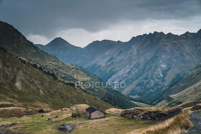 Wide angle of small brick building on grassy field in marvellous Pyrenees mountains under overcast sky in Catalonia — Stock Photo