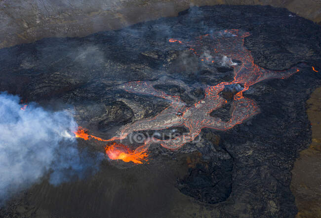 Von oben sprüht Magma aus dem Vulkanloch und fließt in Island wie Lavaflüsse über den Boden — Stockfoto