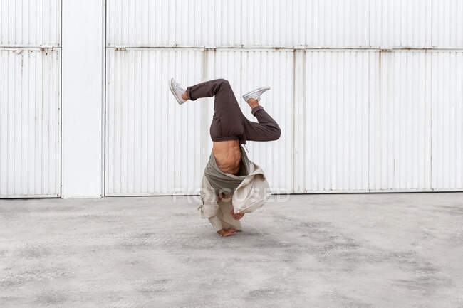 Unerkennbarer männlicher Tänzer zeigt Breakdance-Bewegung beim Balancieren auf den Armen und beim Handhopsen auf Betonboden im Stadtgebiet — Stockfoto