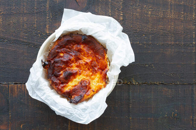 Dall'alto deliziosa torta di formaggio al forno servita su un contenitore in un tavolo di legno — Foto stock