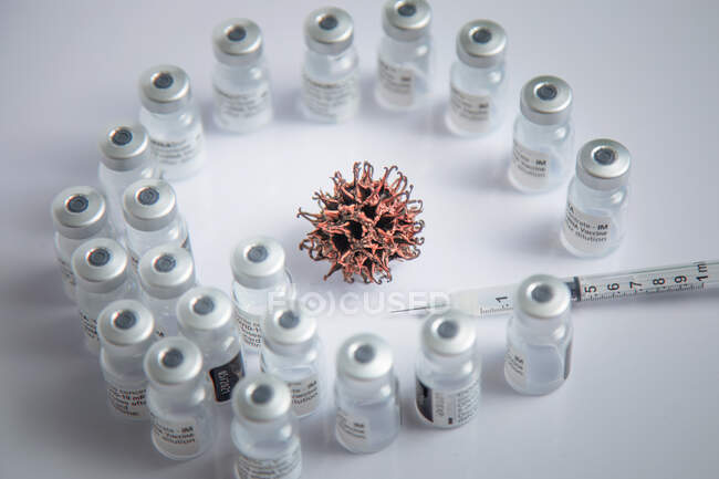 Simulation microscopique du profil du virus COVID-19 en arrière-plan entouré de flacons de vaccin — Photo de stock