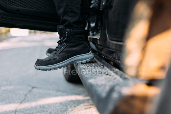 Anonymer Mann und ein paar Füße vor dem Aussteigen aus einem Geländewagen — Stockfoto