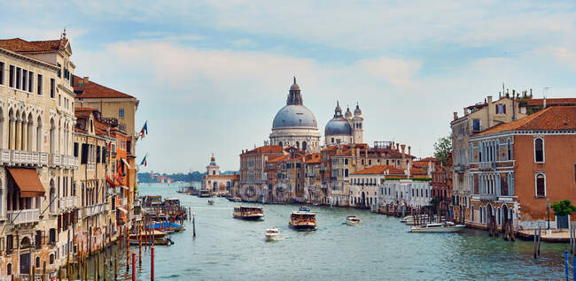 Grande Canal famoso com barcos flutuantes entre edifícios residenciais sob céu azul em Veneza — Fotografia de Stock