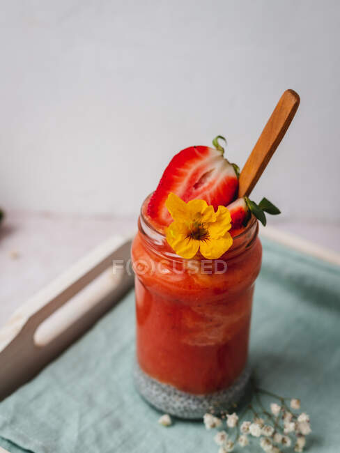 Closeup de um delicioso smoothie de morango com uma guarnição de flor amarela — Fotografia de Stock