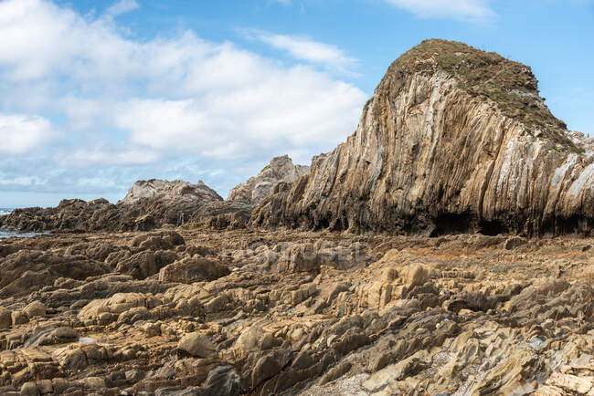 Spettacolare scenario di rocce sulla spiaggia di Gueirua sotto il cielo blu nuvoloso nelle Asturie — Foto stock