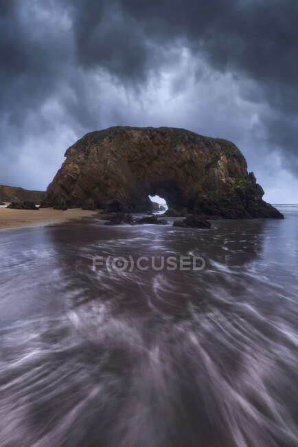 Majestic view of rough rocky formations on wet Penarronda beach under cloudy sky in Asturias — Stock Photo