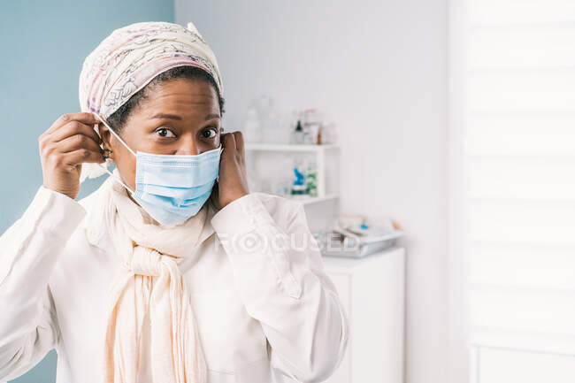 African American mature woman patient with face mask sitting at clinic bed waiting for appointment during appointment during coronavirus outbreak — Stock Photo