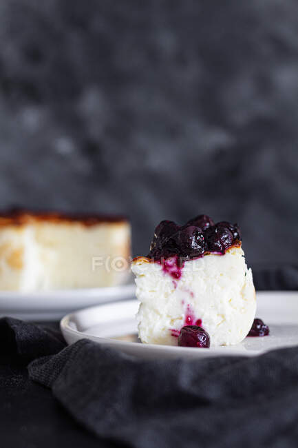 Deliziose fette di cheesecake al forno condite con marmellata di bacche servite su un piatto su sfondo nero — Foto stock