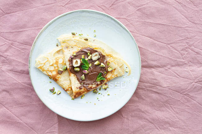 Верхний вид на вкусные блины, украшенные шоколадом и орехами подается на стол на завтрак — стоковое фото