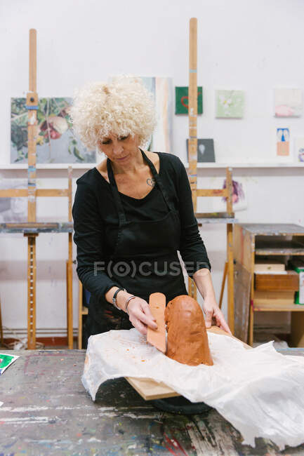 Céramiste féminine utilisant de l'argile et créant de la faïence à la main dans un studio d'art — Photo de stock